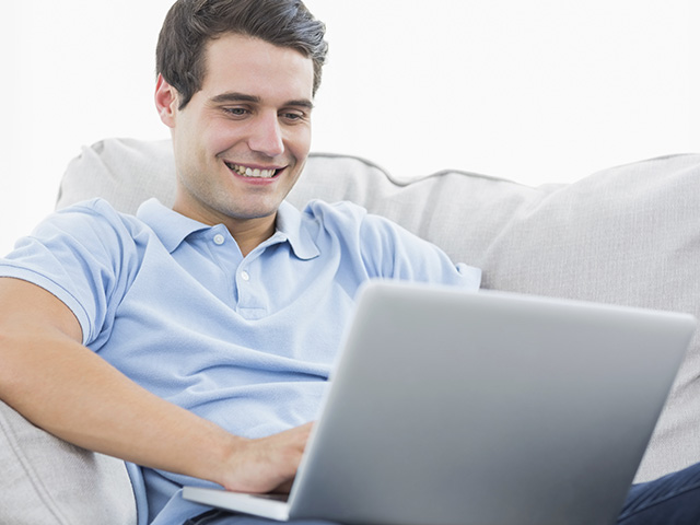 Hombre sentado en el sofá con la laptop en las piernas