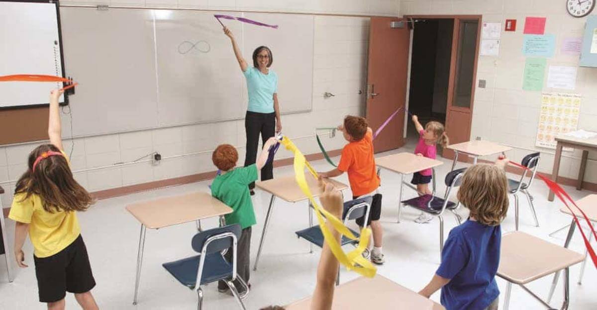Profesora enseñándole a los alumnos como mover los brazos para estirarse