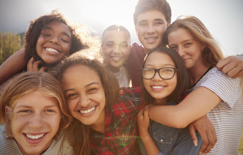 Grupo de 7 adolescentes abrazados y sonriendo