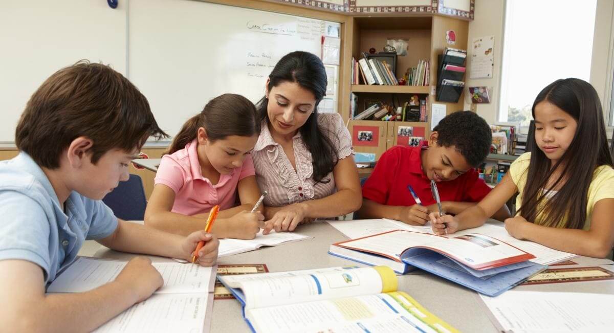 ¿Qué es el aprendizaje inverso? | Profesora acompañando a sus alumnos mientras avanzan ejercicios en sus cuadernos